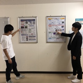 発表しているイメージで２人で記念撮影。<br>２人のポスターは廊下に展示されています。